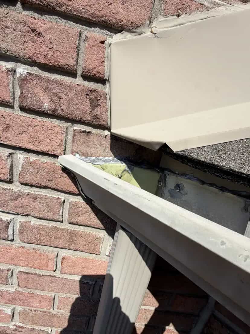 Repaired gutter corner at a brick wall with a downspout below