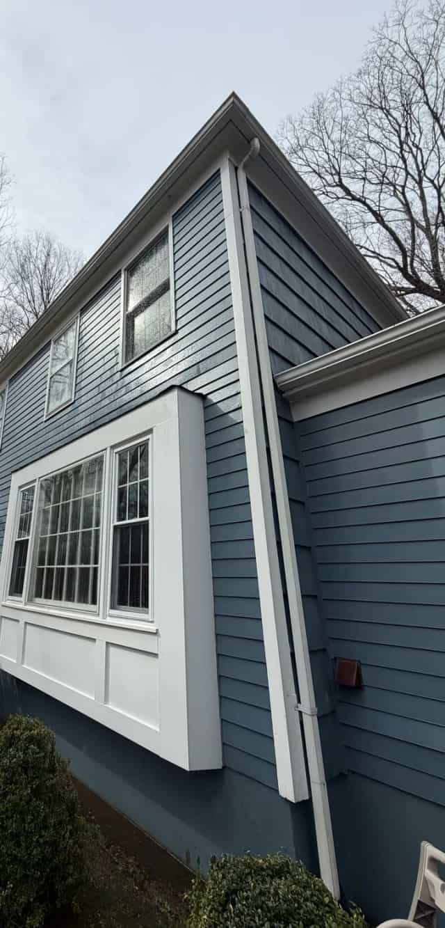 Clean blue clapboard siding and a white bay window after a soft wash