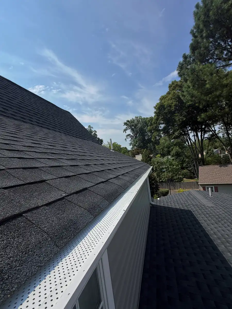 White perforated gutter cover along a grey shingle roof edge