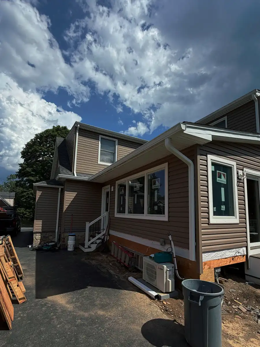 New gutter and downspouts along the roofline of a house with a porch