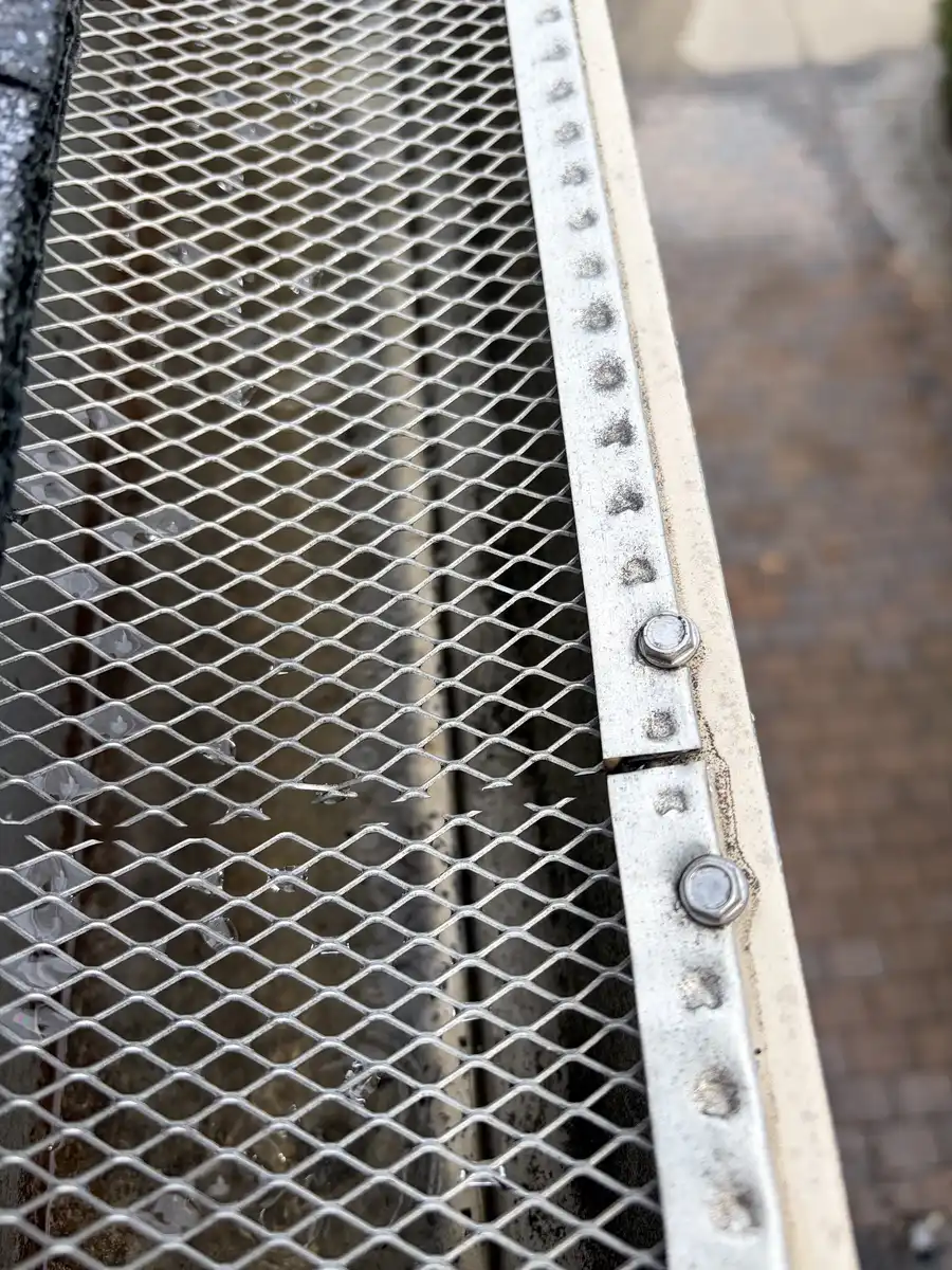 Close-up of mesh gutter guard fastened with screws along a gutter
